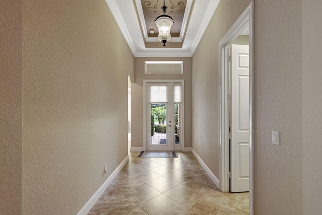 doorway to outside with a tray ceiling and crown molding