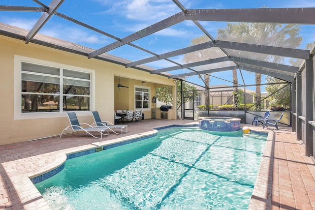 view of swimming pool with a ceiling fan, glass enclosure, a pool with connected hot tub, and a patio area