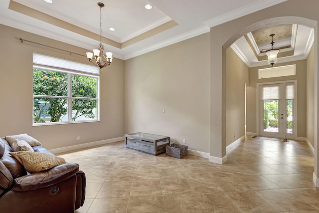 living area featuring a raised ceiling, an inviting chandelier, and ornamental molding