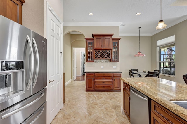 kitchen featuring light stone countertops, appliances with stainless steel finishes, hanging light fixtures, and ornamental molding