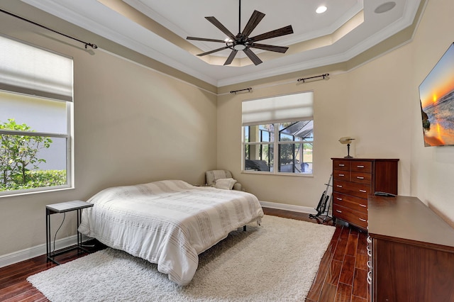 bedroom featuring a raised ceiling, ceiling fan, dark wood-type flooring, and ornamental molding