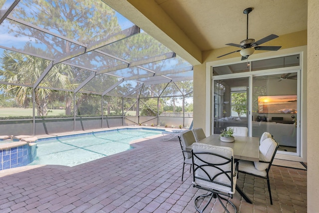 view of swimming pool with glass enclosure, ceiling fan, a patio area, and an outdoor hot tub