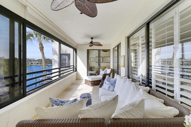 sunroom / solarium with ceiling fan and a water view