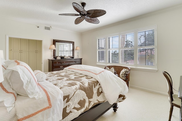 bedroom featuring light carpet, a textured ceiling, ceiling fan, and crown molding