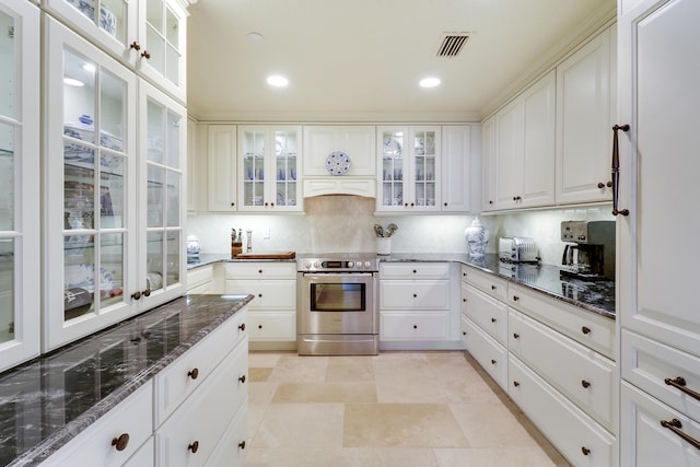 kitchen featuring decorative backsplash, white cabinetry, dark stone counters, and stainless steel range with electric stovetop