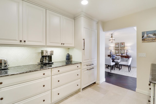 kitchen with tasteful backsplash, white cabinetry, and dark stone counters