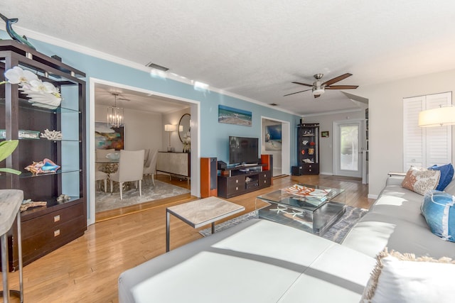 living room featuring ceiling fan with notable chandelier, crown molding, a textured ceiling, and light hardwood / wood-style flooring