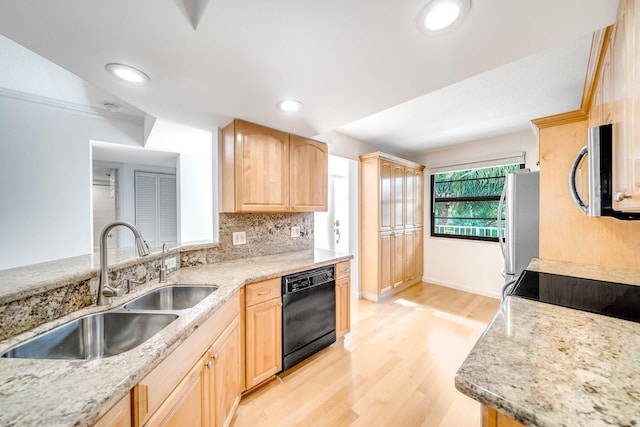 kitchen with appliances with stainless steel finishes, light wood-type flooring, light brown cabinetry, light stone counters, and sink