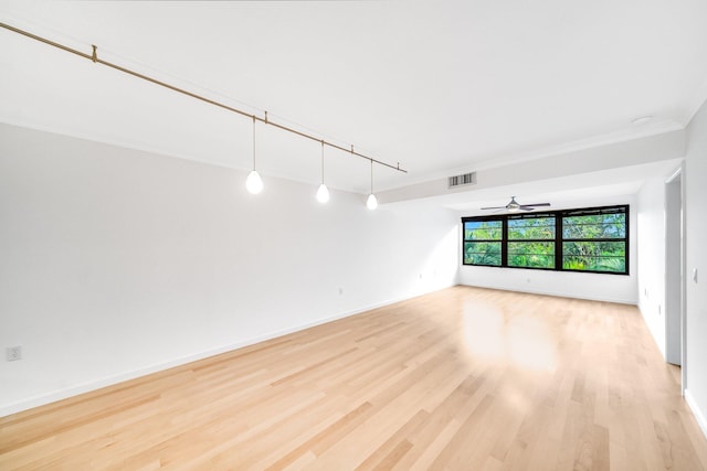 empty room featuring ceiling fan, crown molding, rail lighting, and light hardwood / wood-style floors