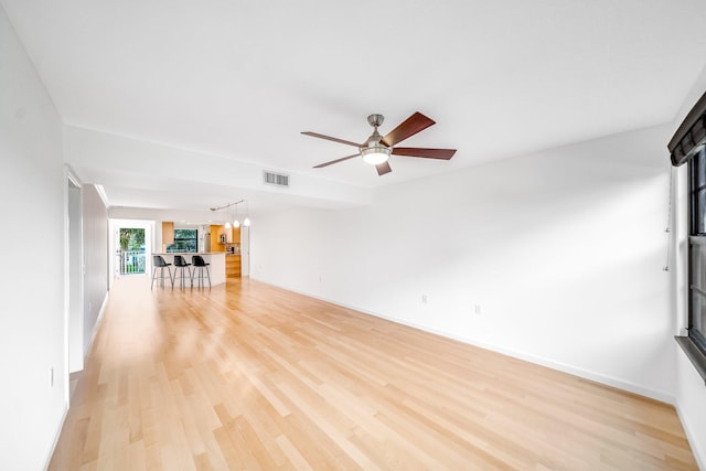 unfurnished living room featuring ceiling fan with notable chandelier and light hardwood / wood-style flooring