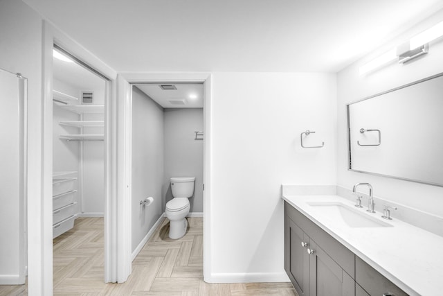 bathroom featuring vanity, toilet, and parquet floors