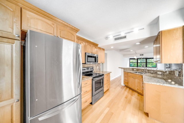 kitchen with appliances with stainless steel finishes, light stone counters, light brown cabinetry, and sink