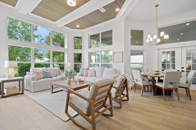 sunroom / solarium featuring beamed ceiling, french doors, a chandelier, and a healthy amount of sunlight