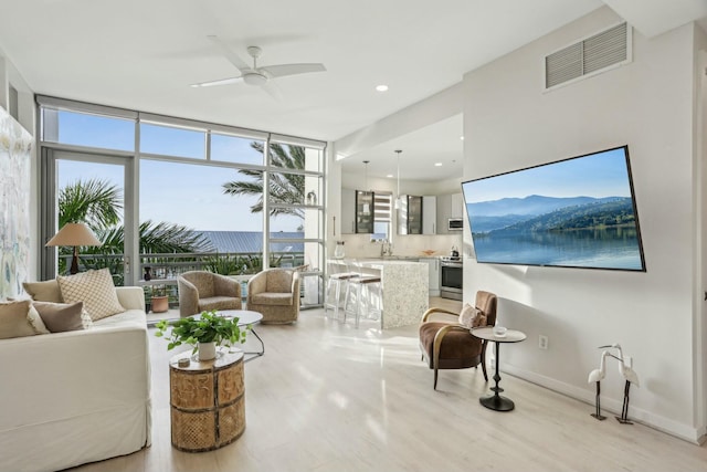 living room with ceiling fan, a wall of windows, and a wealth of natural light