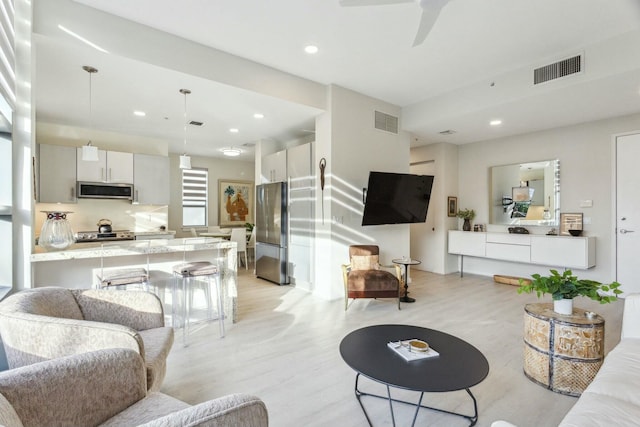 living room with ceiling fan and light hardwood / wood-style flooring