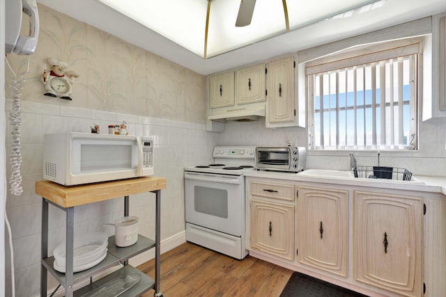 kitchen featuring light wood-type flooring, white appliances, ceiling fan, sink, and light brown cabinets