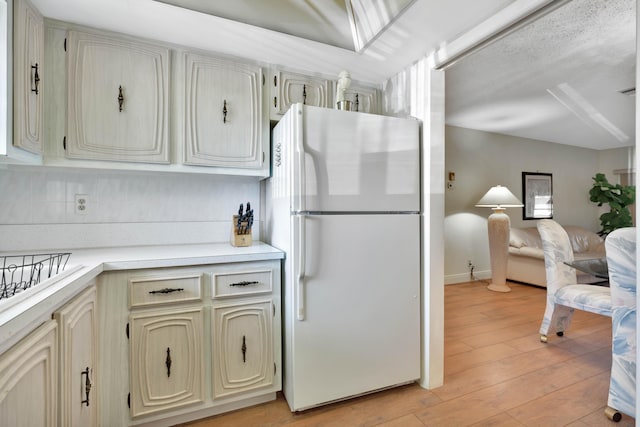 kitchen featuring cream cabinetry, light wood-type flooring, and white refrigerator