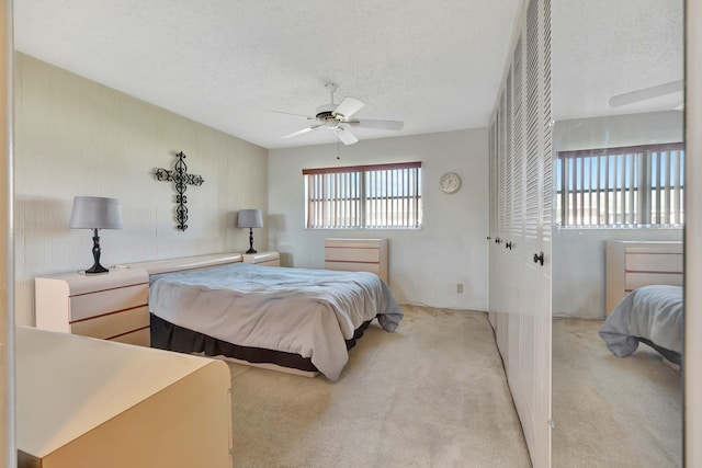 carpeted bedroom with a textured ceiling, a closet, and ceiling fan