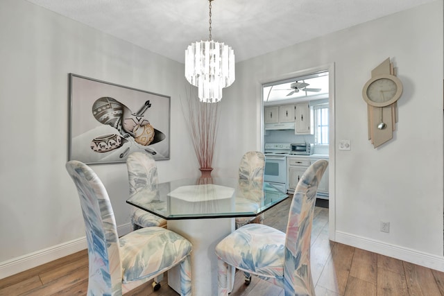 dining space featuring ceiling fan with notable chandelier and a textured ceiling