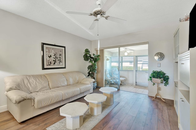 living room featuring wood-type flooring, a textured ceiling, and ceiling fan