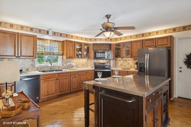 kitchen featuring sink, ceiling fan, light wood-type flooring, appliances with stainless steel finishes, and a kitchen island