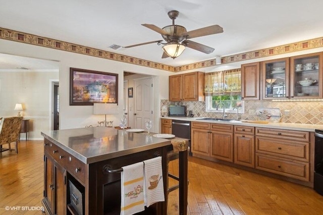 kitchen with light wood-type flooring, a center island, tasteful backsplash, and sink