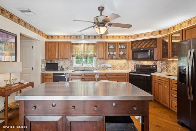 kitchen featuring ceiling fan, a center island, sink, backsplash, and black appliances