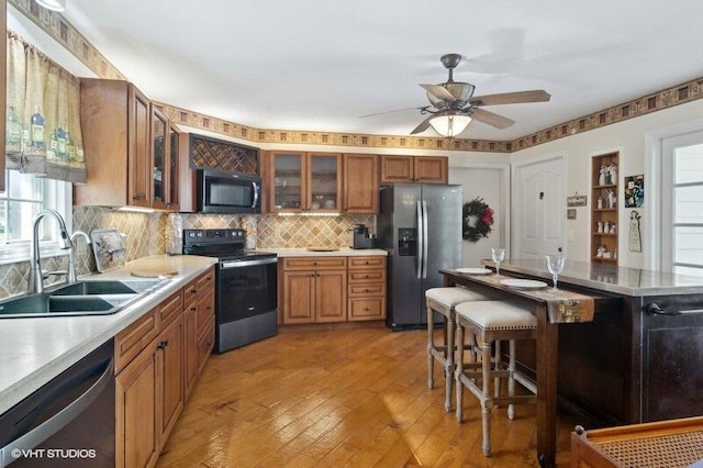 kitchen with ceiling fan, sink, a kitchen bar, decorative backsplash, and appliances with stainless steel finishes