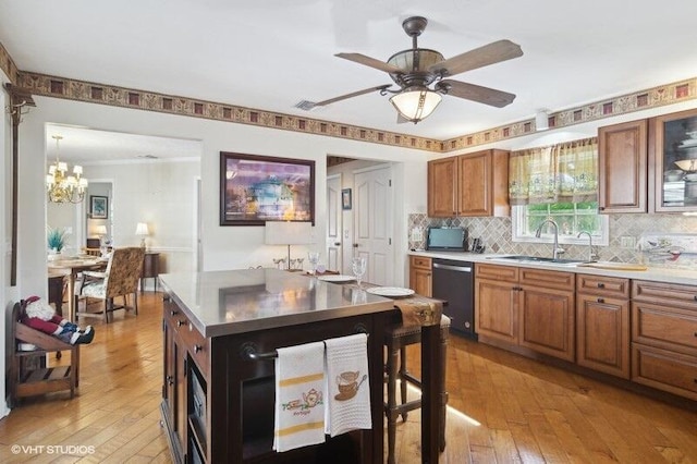 kitchen featuring sink, stainless steel dishwasher, backsplash, ceiling fan with notable chandelier, and light wood-type flooring