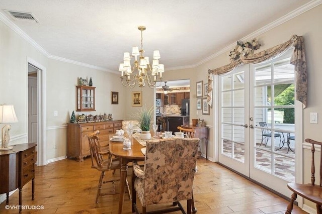 dining room featuring a chandelier, light hardwood / wood-style floors, crown molding, and french doors