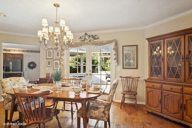 dining area featuring crown molding, hardwood / wood-style floors, french doors, and an inviting chandelier