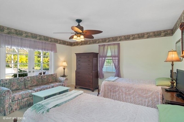 bedroom with multiple windows, ceiling fan, french doors, and light colored carpet