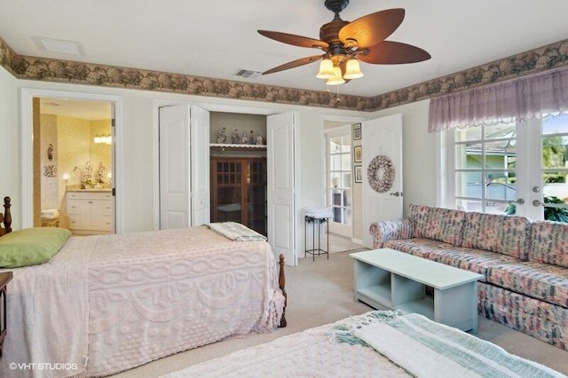 bedroom featuring multiple windows, ceiling fan, ensuite bathroom, and light carpet