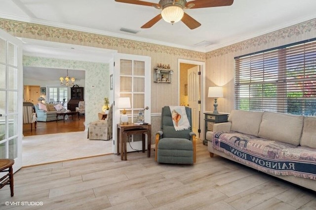 living room featuring ceiling fan with notable chandelier, light hardwood / wood-style floors, and ornamental molding