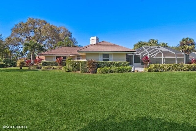 back of house featuring a yard and glass enclosure