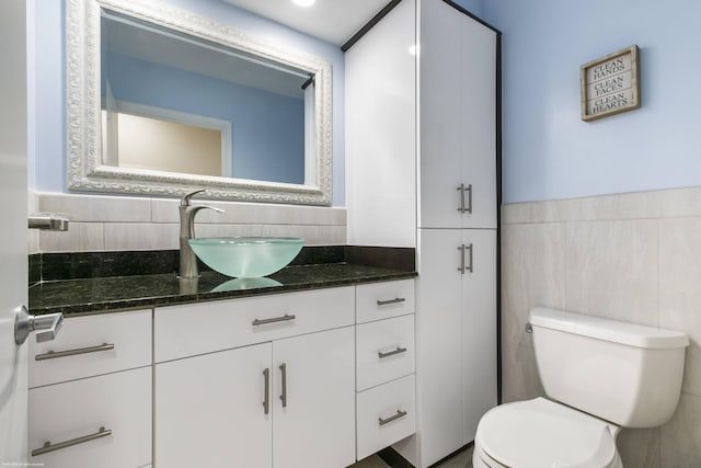 bathroom featuring vanity, tile walls, and toilet