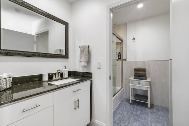 bathroom with vanity, combined bath / shower with glass door, tile walls, and tile patterned floors