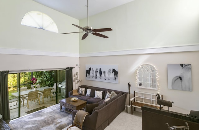 living room featuring ceiling fan, light tile patterned floors, and a high ceiling