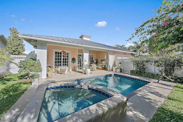 rear view of house featuring a pool with hot tub and a patio