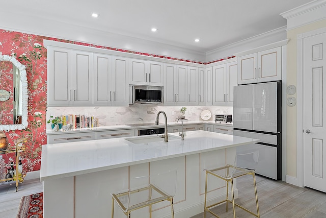 kitchen featuring white cabinets, refrigerator, a kitchen bar, and an island with sink