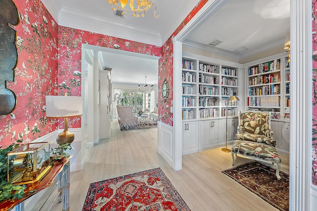 hallway with built in shelves, light hardwood / wood-style flooring, an inviting chandelier, and ornamental molding