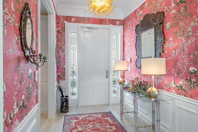 foyer with crown molding and an inviting chandelier