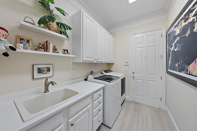 laundry area featuring cabinets, sink, light hardwood / wood-style flooring, washing machine and dryer, and ornamental molding