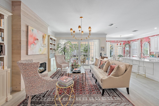 living room with a fireplace, ornamental molding, light hardwood / wood-style flooring, and a chandelier