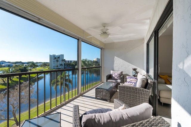 balcony with a sunroom, a water view, ceiling fan, and an outdoor living space