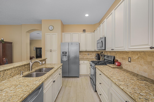 kitchen with white cabinetry, sink, light stone counters, and appliances with stainless steel finishes