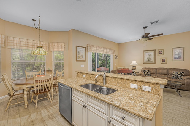 kitchen featuring sink, hanging light fixtures, light stone counters, an island with sink, and stainless steel dishwasher