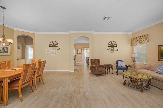 living room featuring crown molding, light hardwood / wood-style floors, a chandelier, and a textured ceiling