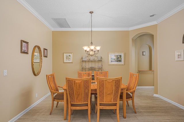 dining room with ornamental molding, an inviting chandelier, and light hardwood / wood-style floors