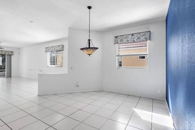 unfurnished room with a wealth of natural light, baseboards, and light tile patterned floors